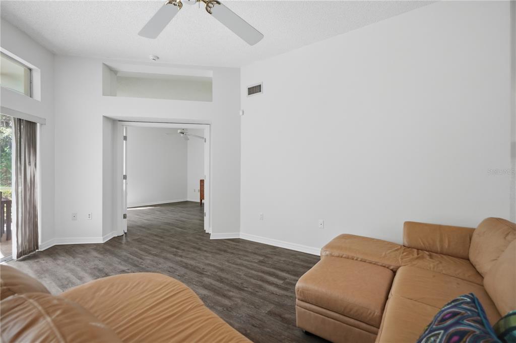 A living room with light walls, wood-look flooring, a ceiling fan, and a tan sectional — 215 CLAYS TRAIL, OLDSMAR, FL