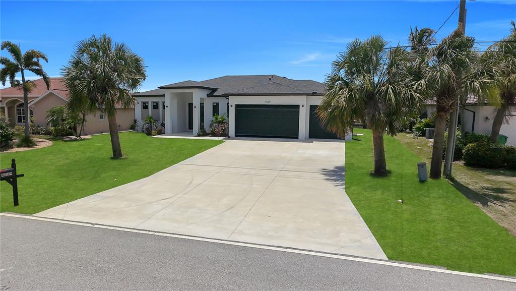 A single-story house with a concrete driveway, a three-car garage, and palm trees in front — 4129 FLAMINGO BOULEVARD, PORT CHARLOTTE, FL