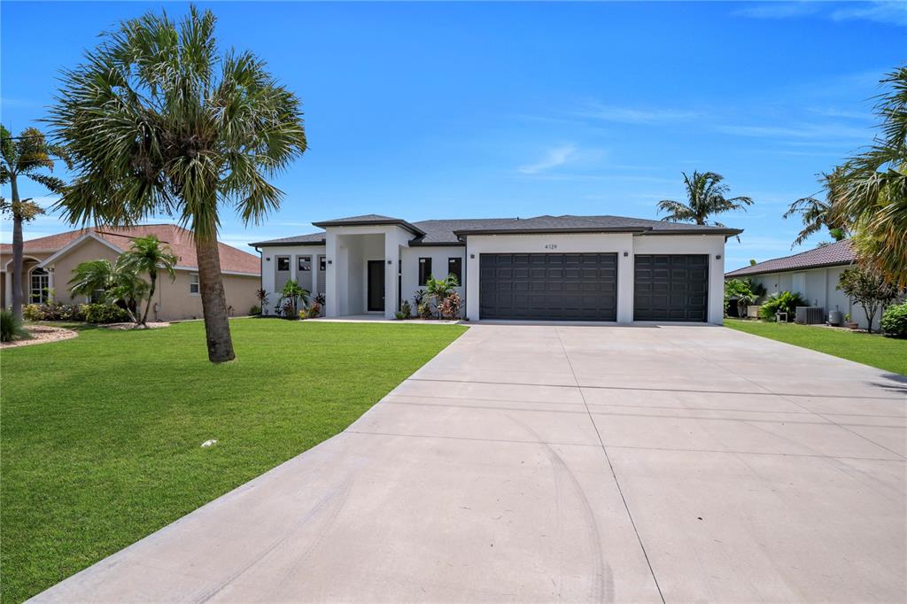 A modern single-story house with a white exterior, dark garage doors, and a concrete driveway — 4129 FLAMINGO BOULEVARD, PORT CHARLOTTE, FL