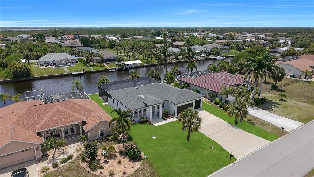 An aerial view shows a suburban neighborhood with houses, canals, and palm trees — 4129 FLAMINGO BOULEVARD, PORT CHARLOTTE, FL