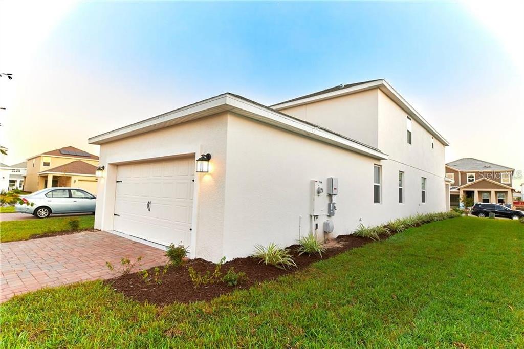 A side view of a two-story house with a white stucco exterior and a garage — 12027 GRAMMAR LANE, ORLANDO, FL