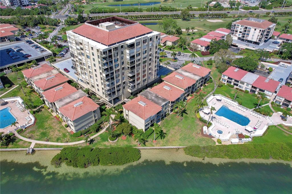 An aerial view shows a multi-story apartment building surrounded by smaller residential units and pools — 6322 PALMA DEL MAR BOULEVARD S UNIT 505, ST PETERSBURG, FL