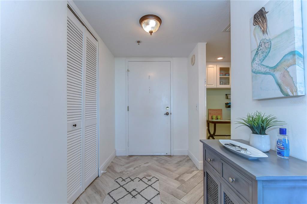 An entryway features a white door, louvered closet doors, wood-look tile flooring, and a console table — 6322 PALMA DEL MAR BOULEVARD S UNIT 505, ST PETERSBURG, FL