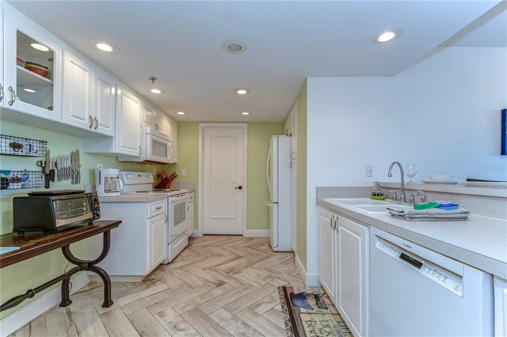 A kitchen with white cabinets, light countertops, a herringbone floor, and stainless steel appliances — 6322 PALMA DEL MAR BOULEVARD S UNIT 505, ST PETERSBURG, FL