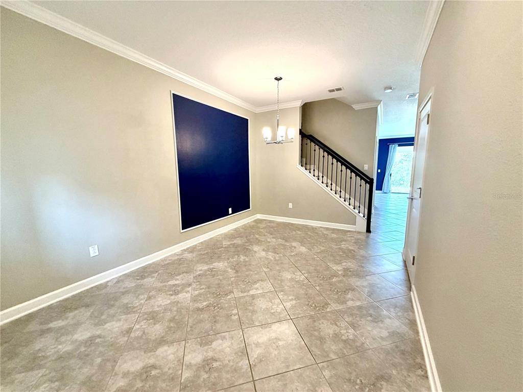 A dining room features tile flooring, a dark blue accent wall, and a staircase — 1344 ROYAL ST GEORGE BOULEVARD, DAVENPORT, FL