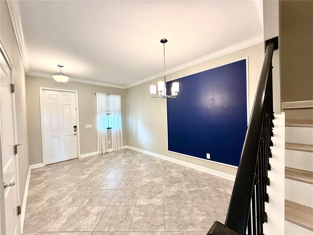 A dining area features tile flooring, a blue accent wall, and a modern chandelier — 1344 ROYAL ST GEORGE BOULEVARD, DAVENPORT, FL