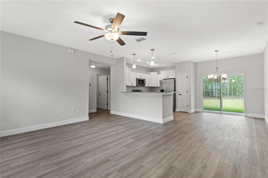 An open-concept living and dining area features light gray walls, wood-look flooring, and a kitchen — 4372 MERCEDES STREET, SEBRING, FL