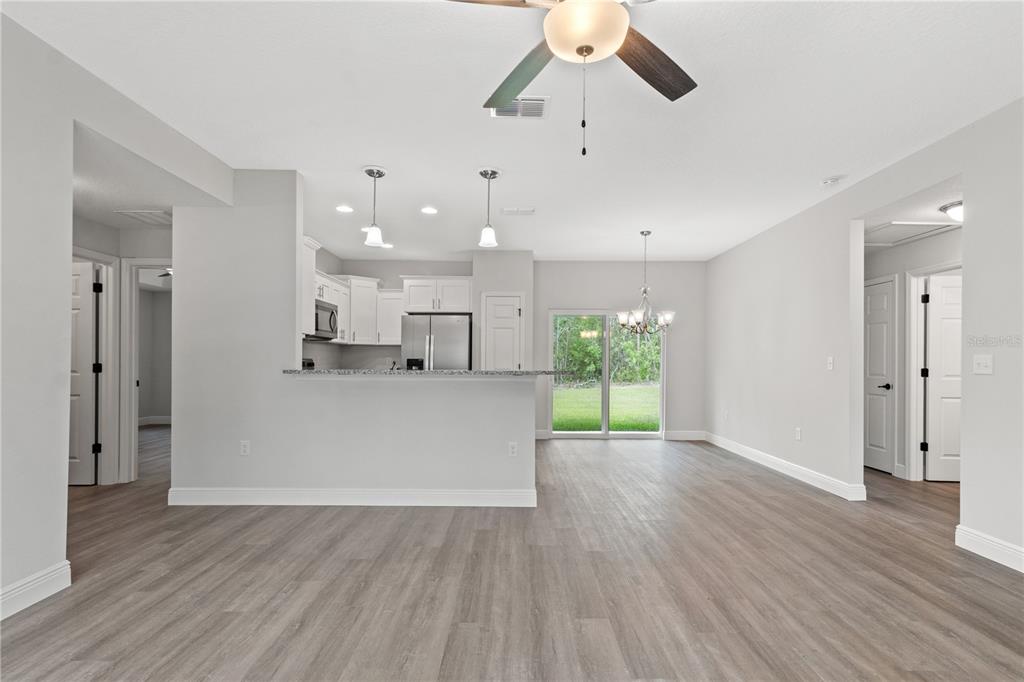 An open-concept kitchen and living area feature light gray walls and wood-look flooring — 4372 MERCEDES STREET, SEBRING, FL