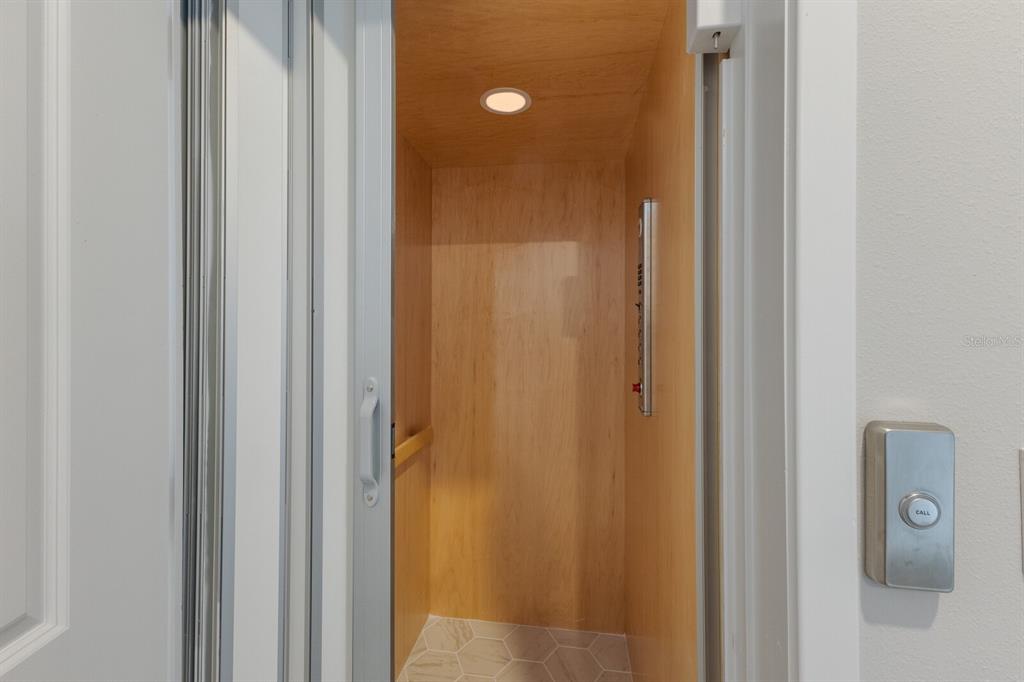A residential elevator with wood-paneled walls, a recessed ceiling light, and a call button — 7420 NEWHAM LANE, SARASOTA, FL