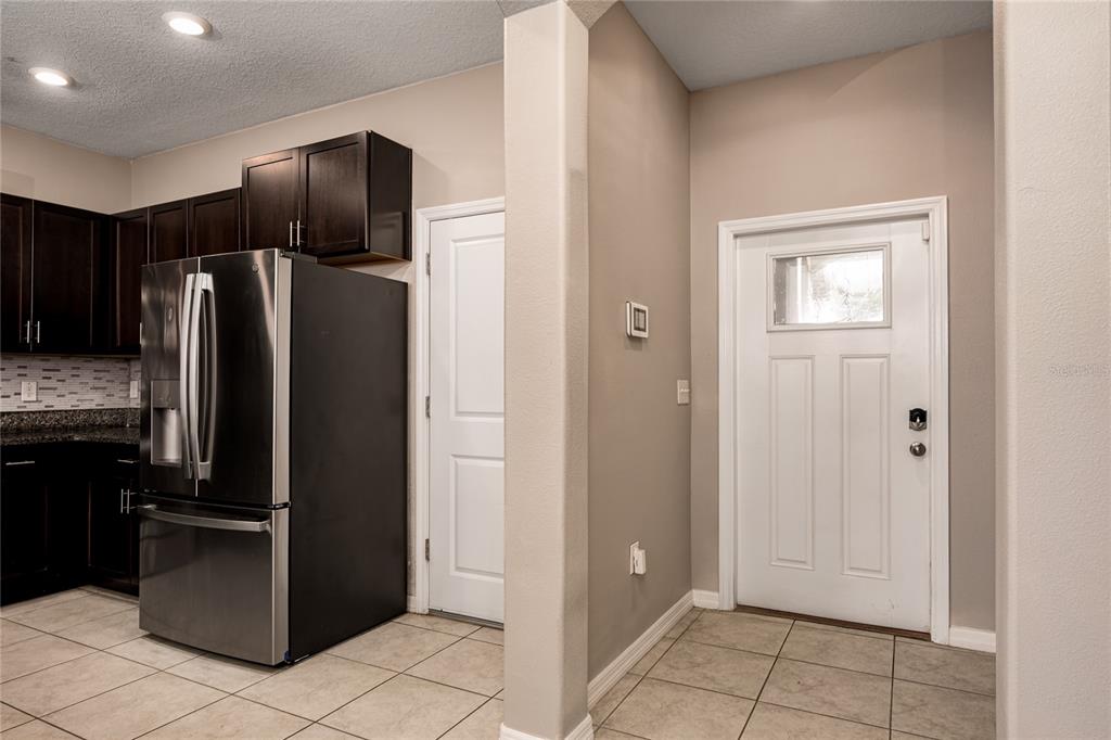 A kitchen with dark cabinets and stainless steel appliances sits next to a white door — 724 ROYAL EMPRESS DRIVE, RUSKIN, FL