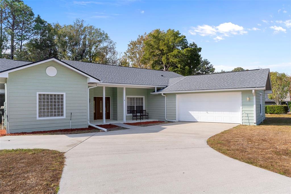 A light green single-story house features a white garage door and a concrete driveway — 9 FOXGREEN COURT, HOMOSASSA, FL