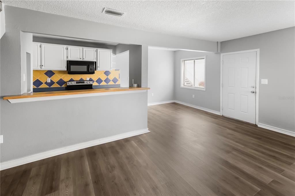 A kitchen with a breakfast bar overlooks a living area with wood-look flooring — 1829 BOUGH AVENUE UNIT 3, CLEARWATER, FL