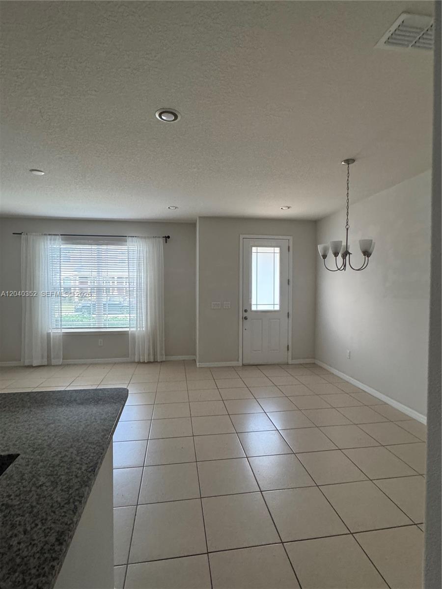 An open-concept dining area features tile flooring, a chandelier, and a front entry door — 2713 Giardino Loop # 0, Kissimmee FL 34741, KISSIMMEE, FL