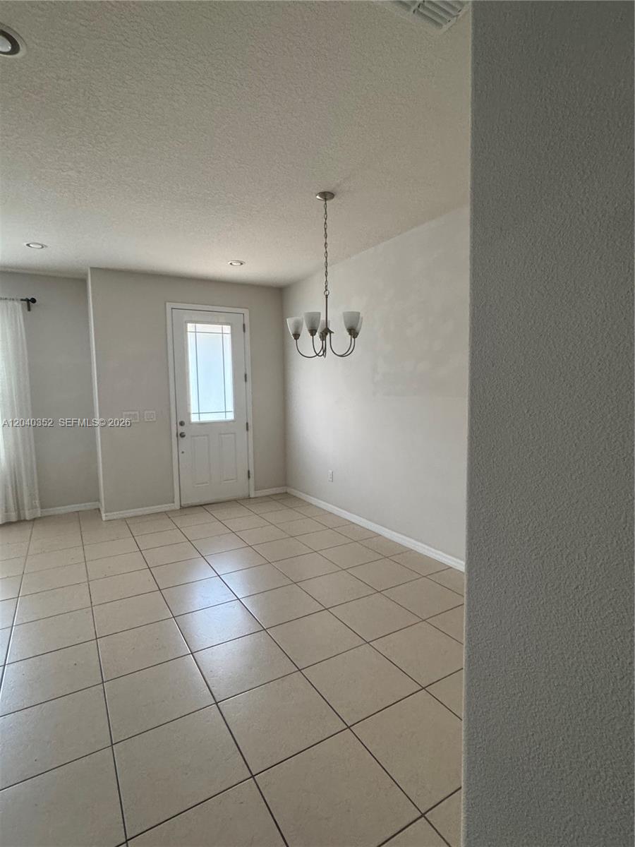 A dining area features light-colored tile flooring, a chandelier, and a white exterior door — 2713 Giardino Loop # 0, Kissimmee FL 34741, KISSIMMEE, FL
