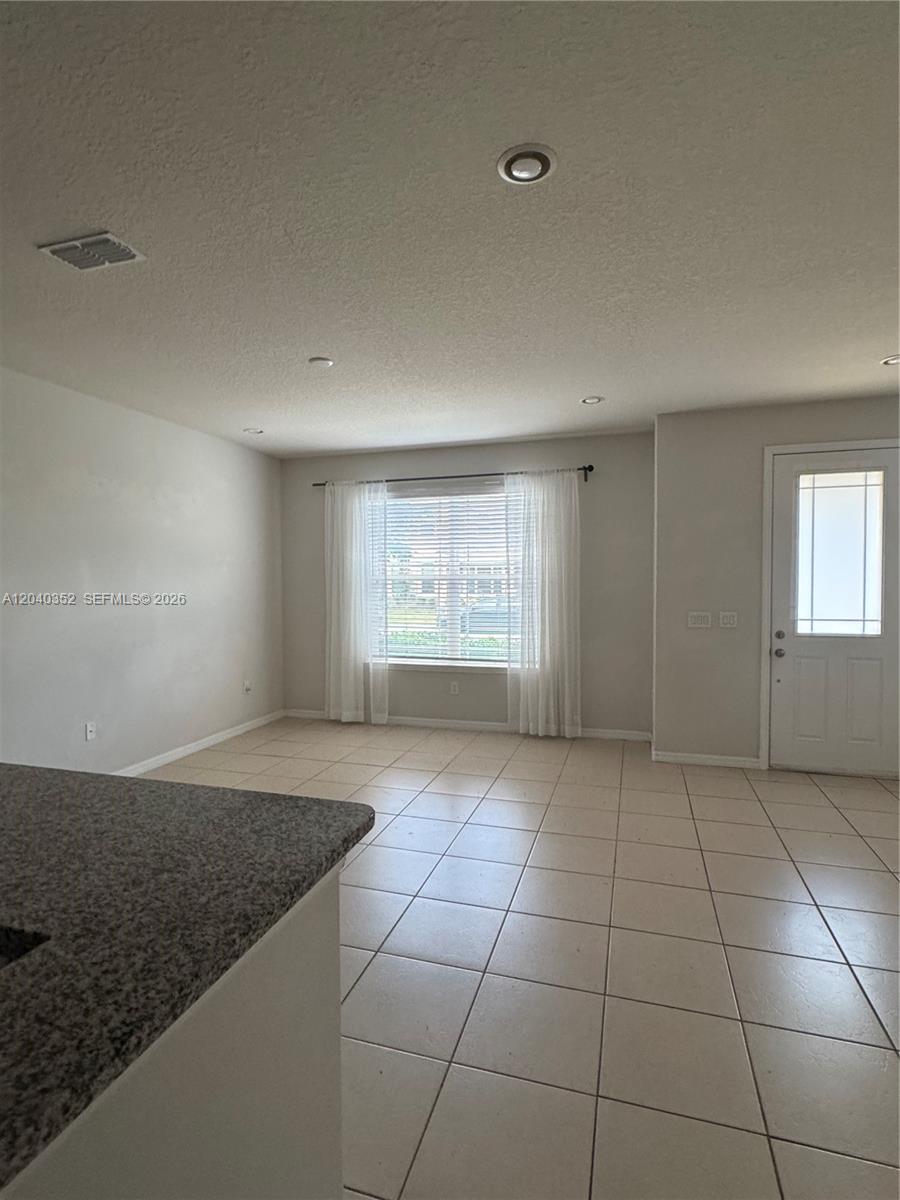 This room features light-colored tile flooring, neutral walls, recessed lighting, and a window with curtains — 2713 Giardino Loop # 0, Kissimmee FL 34741, KISSIMMEE, FL