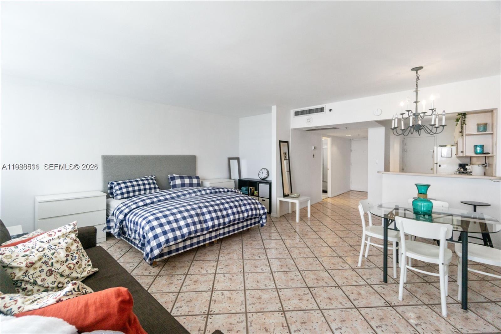 A studio apartment features a bed, a dining set, and tile flooring throughout the space — 100 Lincoln Rd # 818, Miami Beach FL 33139, MIAMI BEACH, FL