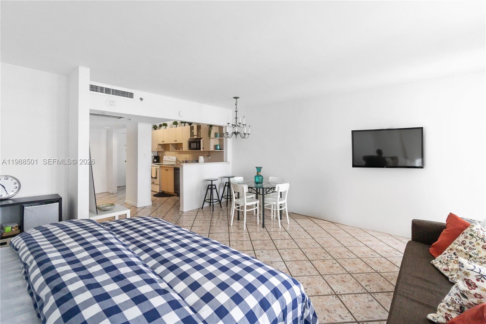 A studio apartment features a bed, dining area, kitchen, and a wall-mounted television — 100 Lincoln Rd # 818, Miami Beach FL 33139, MIAMI BEACH, FL