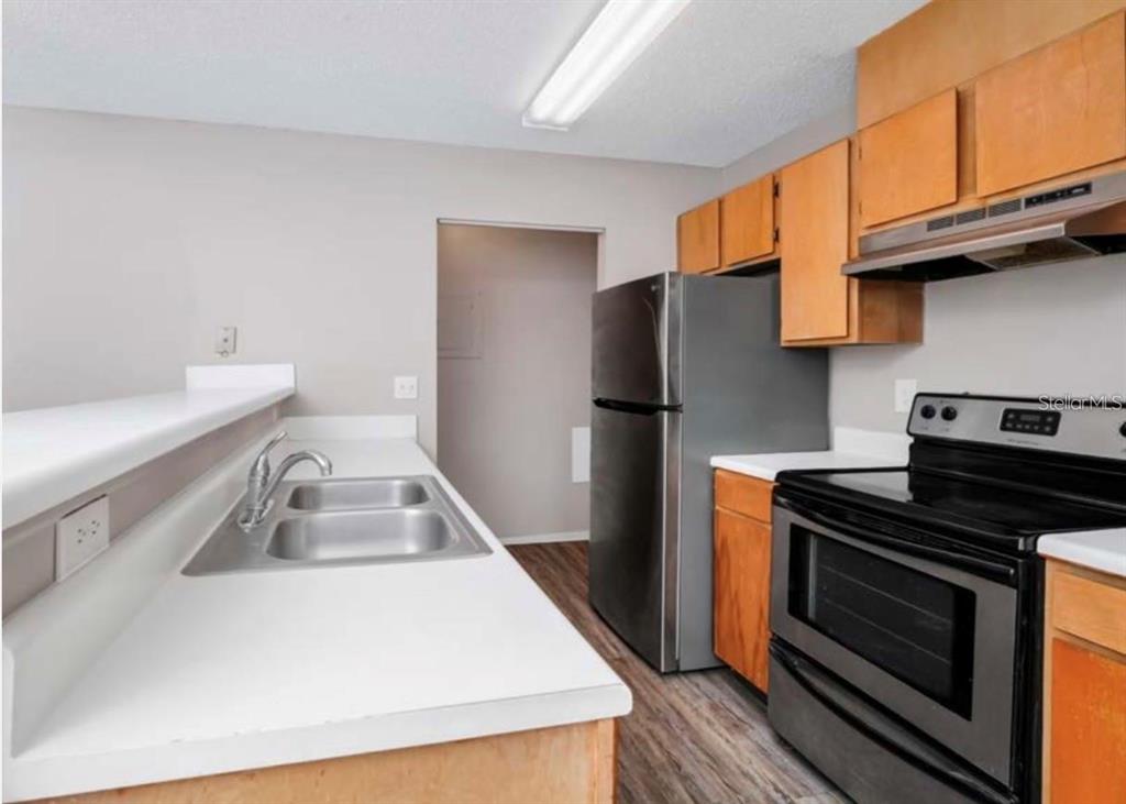 A kitchen features wood cabinets, stainless steel appliances, a double sink, and white countertops — 7298 ULMERTON ROAD ROAD UNIT 602, LARGO, FL