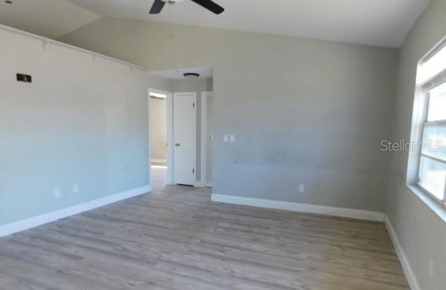An empty room with light gray walls, wood-look flooring, and a ceiling fan — 705 SW 9TH COURT, CAPE CORAL, FL