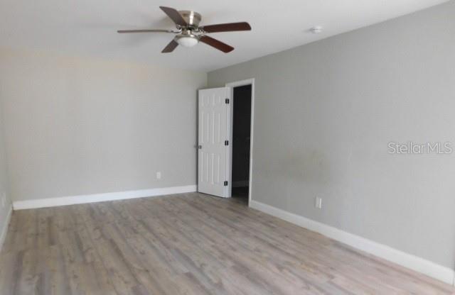 An empty room with light gray walls, wood-look flooring, and a ceiling fan — 705 SW 9TH COURT, CAPE CORAL, FL