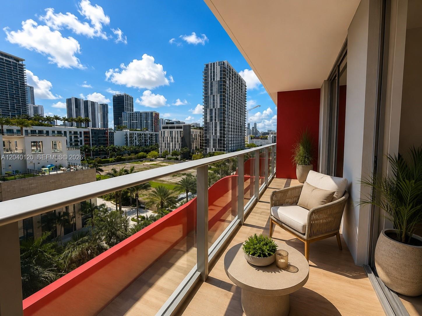 A balcony with a chair, small table, and red accent wall overlooks a city skyline — 90 NE 32nd St # 705, Miami FL 33137, MIAMI, FL
