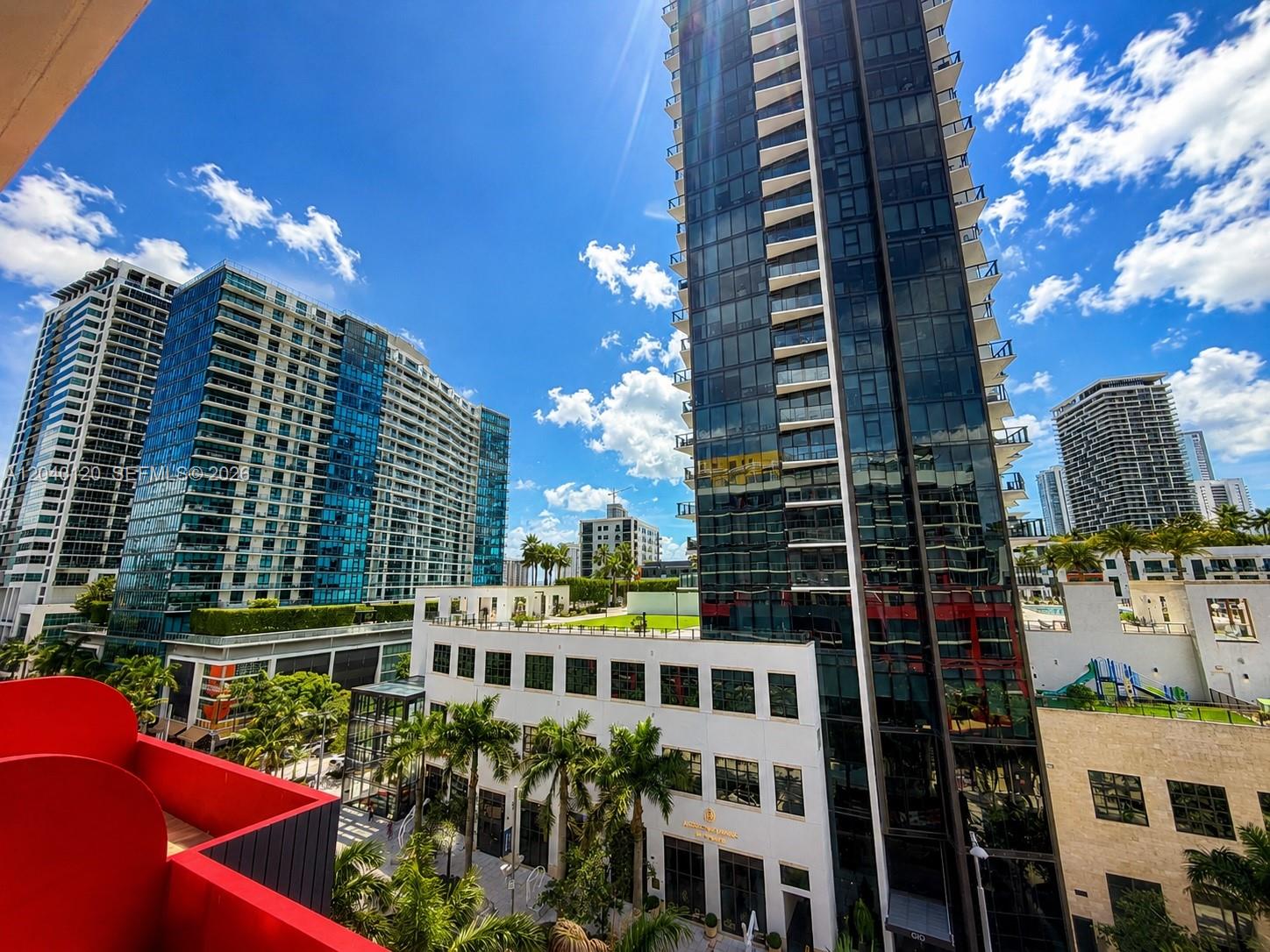 A high-angle view of modern glass skyscrapers and a white building with palm trees — 90 NE 32nd St # 705, Miami FL 33137, MIAMI, FL