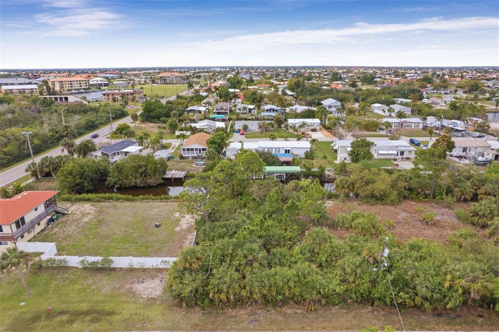 An aerial view shows a vacant lot with dense vegetation and a small canal — 3111 BANYAN WAY, PUNTA GORDA, FL