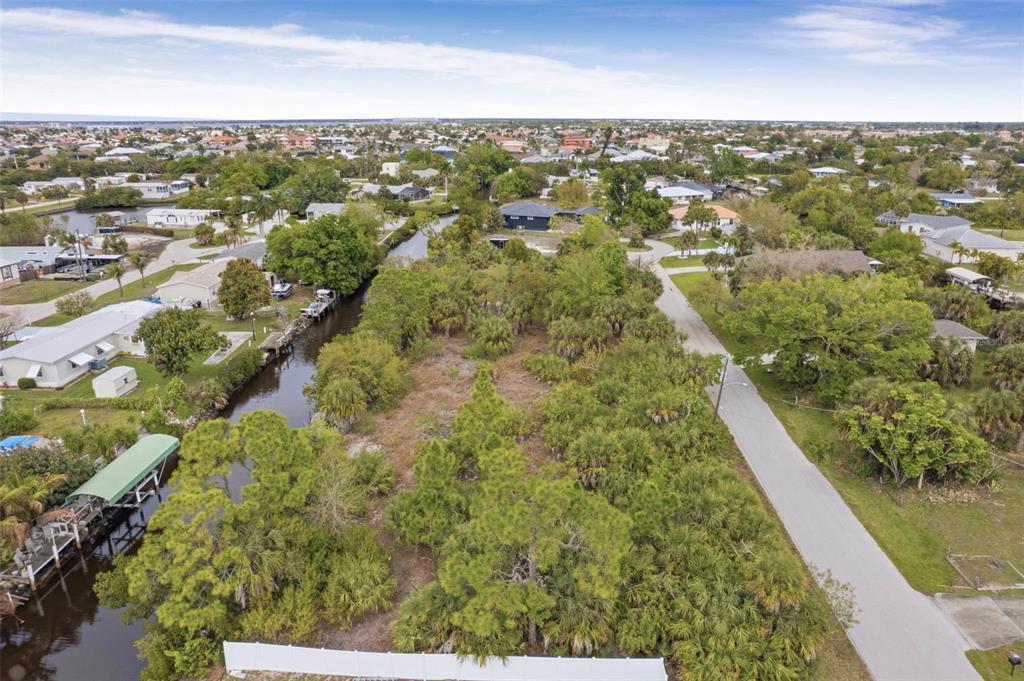 An aerial view shows a vacant, tree-covered lot situated between a canal and a road — 3111 BANYAN WAY, PUNTA GORDA, FL