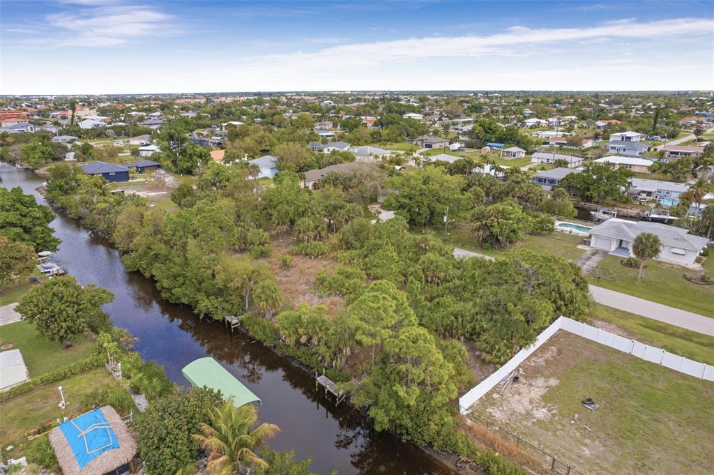 An aerial view shows a vacant, tree-covered lot situated along a narrow canal — 3111 BANYAN WAY, PUNTA GORDA, FL