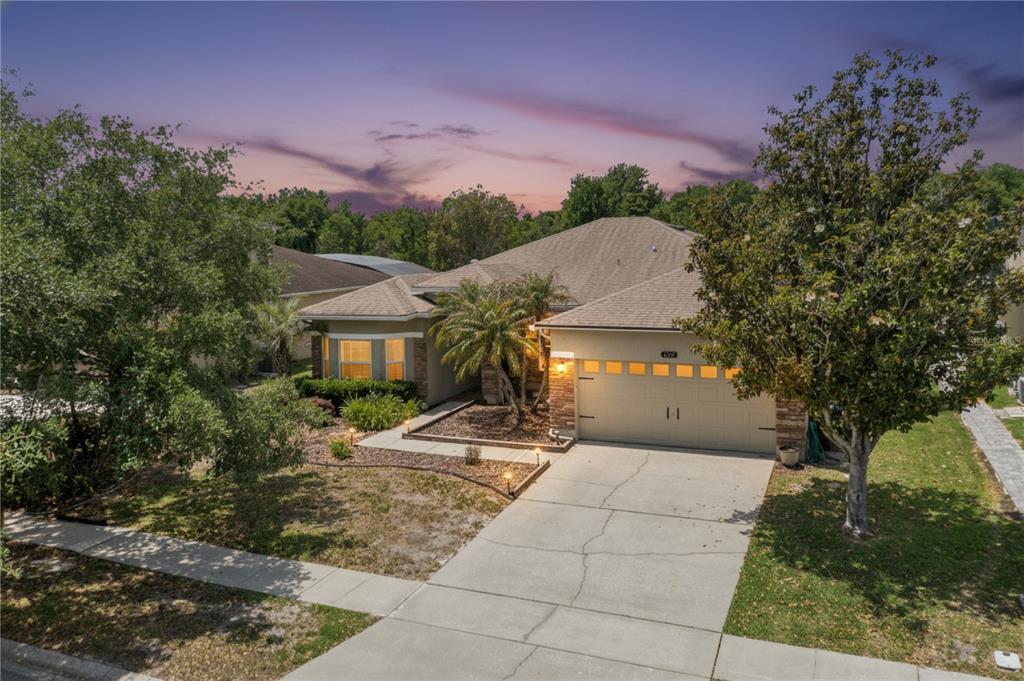 An exterior view of a single-story house with a two-car garage and a paved driveway — 237 STRATHMORE CIRCLE, KISSIMMEE, FL