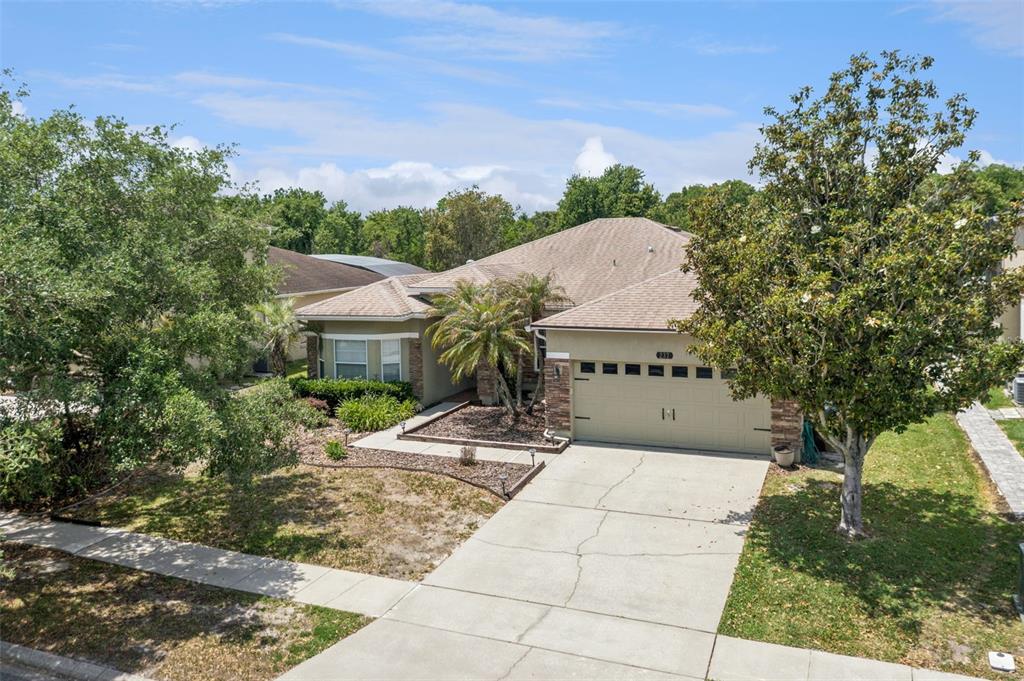An exterior view of a single-story suburban house with a concrete driveway and landscaped yard — 237 STRATHMORE CIRCLE, KISSIMMEE, FL