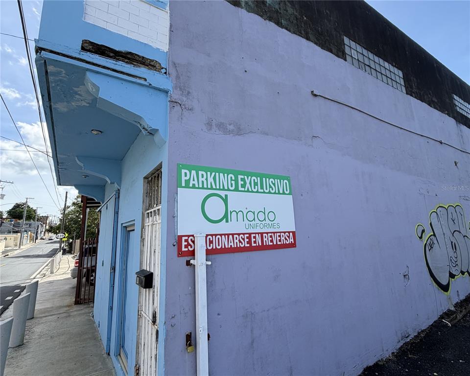 A sign for Amado Uniformes is mounted on the purple exterior wall of a building — 839 C. HIRAM GONZÁLEZ, BAYAMON, PR