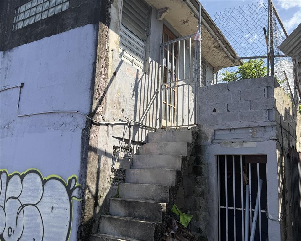 An exterior view of a concrete building with an outdoor staircase and a metal gate — 839 C. HIRAM GONZÁLEZ, BAYAMON, PR