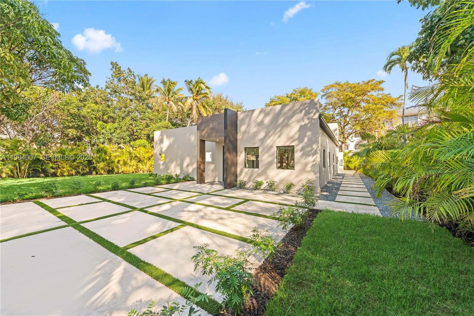 A modern, flat-roofed house with a concrete paver driveway and lush tropical landscaping — 12335 Griffing Blvd, North Miami FL 33161, NORTH MIAMI, FL
