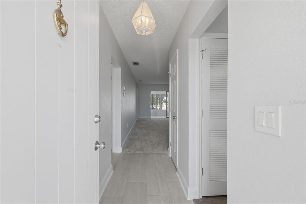 A view from an entryway looking down a hallway toward a carpeted living area — 9917 DESOTO COURT UNIT 9917, BRADENTON, FL