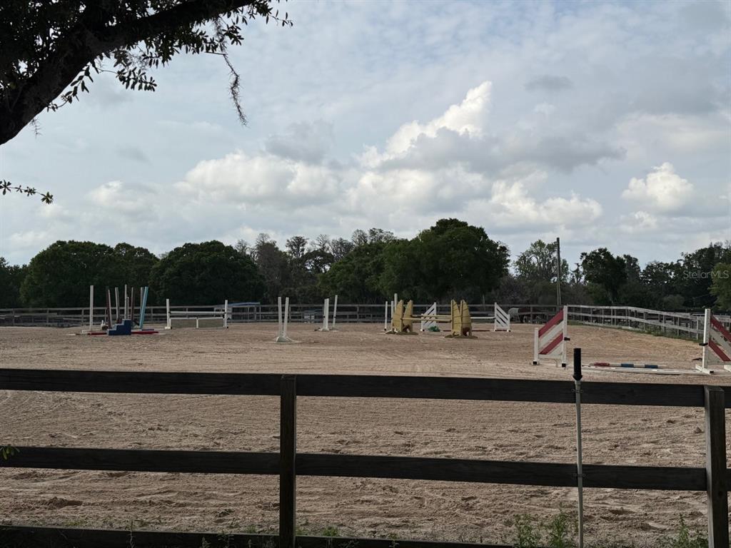 An outdoor horse riding arena features several jumps set within a fenced dirt enclosure — 16315 MCGLAMERY ROAD, ODESSA, FL