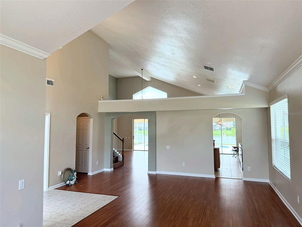 An open-concept living area features vaulted ceilings, dark wood flooring, and a view of a pool — 2361 MID PINE COURT, OVIEDO, FL