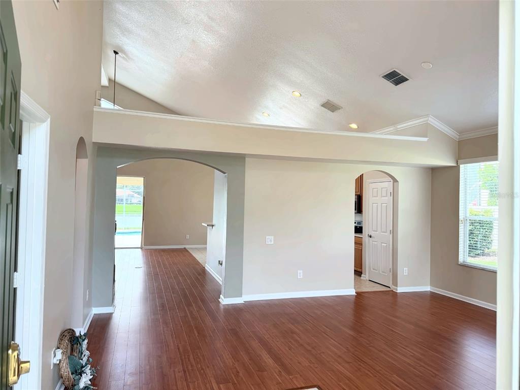 An interior view of a living area with vaulted ceilings, wood-look flooring, and arched doorways — 2361 MID PINE COURT, OVIEDO, FL