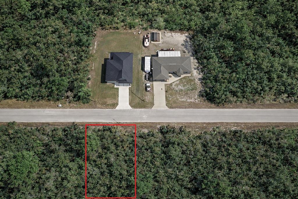 An aerial view shows a vacant, wooded lot outlined in red across from two houses — FISHER LOOP PASS, OCKLAWAHA, FL