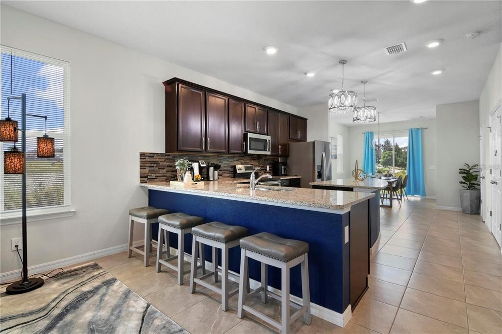 A kitchen features dark wood cabinets, granite countertops, a blue island, and four bar stools — 294 ABERDEEN STREET, DAVENPORT, FL