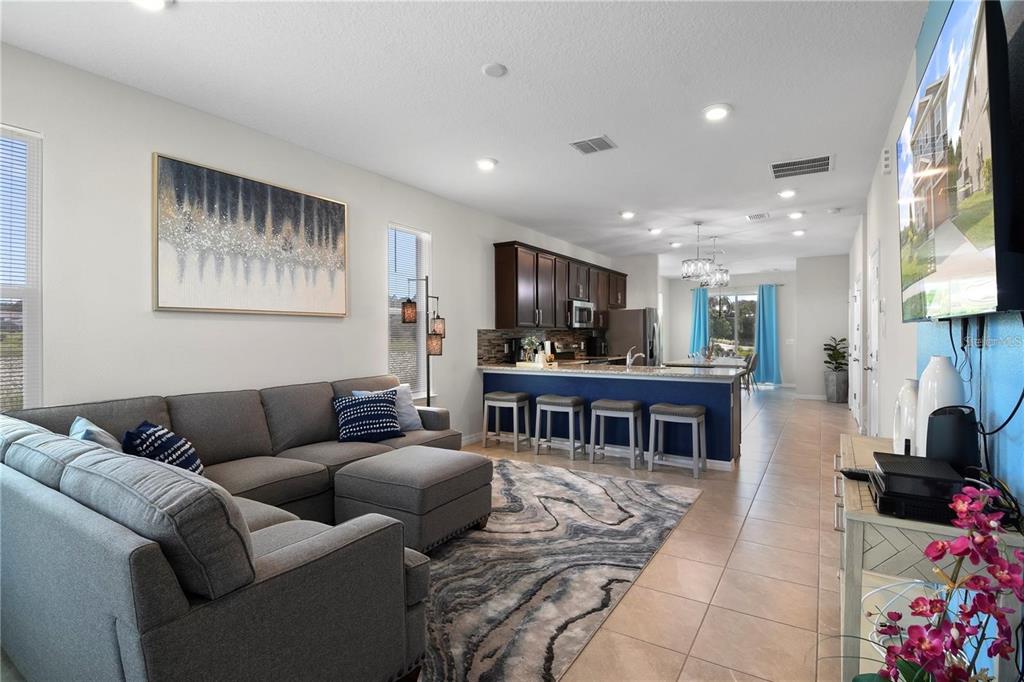 A living room with a gray sectional sofa opens to a kitchen with blue cabinetry — 294 ABERDEEN STREET, DAVENPORT, FL