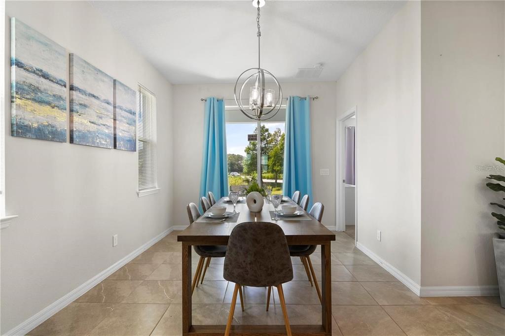A dining room features a wooden table, six chairs, a chandelier, and blue curtains — 294 ABERDEEN STREET, DAVENPORT, FL