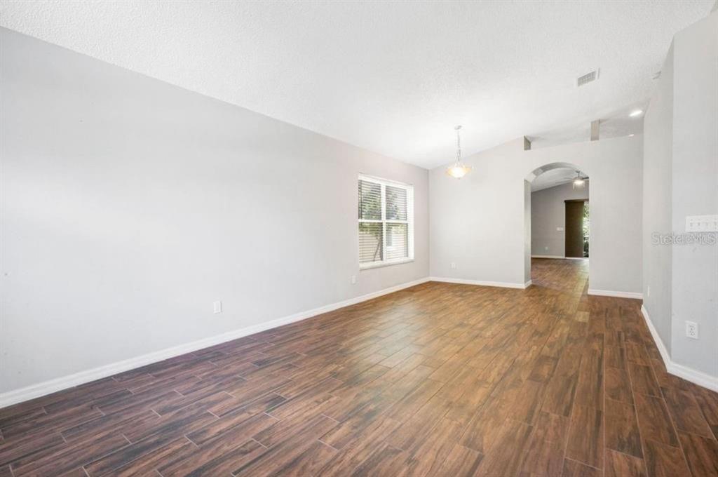 An empty room with wood-look tile flooring, light gray walls, and an arched doorway — 14795 YORKSHIRE RUN DRIVE, ORLANDO, FL
