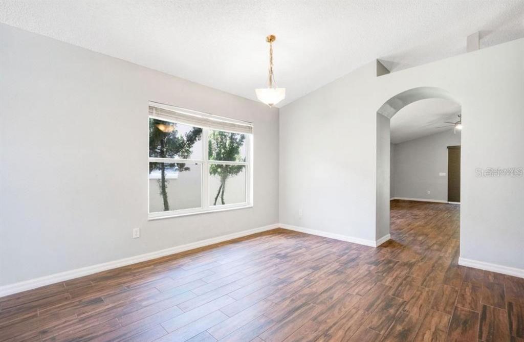 A dining room with light gray walls, wood-look tile flooring, and a vaulted ceiling — 14795 YORKSHIRE RUN DRIVE, ORLANDO, FL