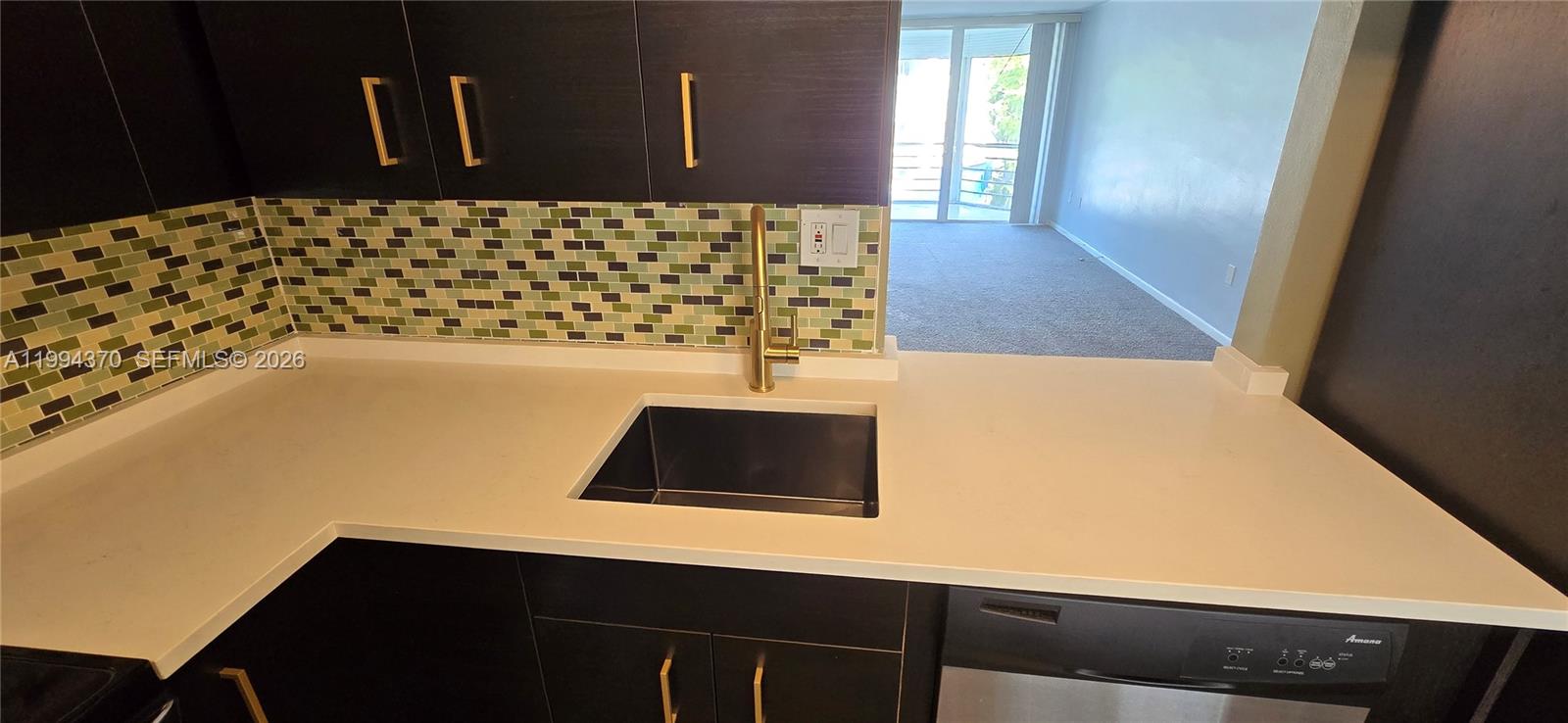 A kitchen features dark cabinets, a white countertop, a black sink, and a mosaic backsplash — 1201 NE 191st St # G306, Miami FL 33179, MIAMI, FL