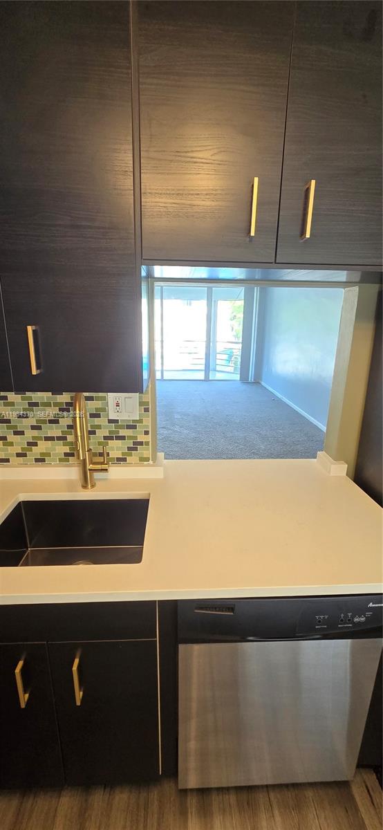 A kitchen features dark wood cabinets, a white countertop, a mosaic backsplash, and a dishwasher — 1201 NE 191st St # G306, Miami FL 33179, MIAMI, FL