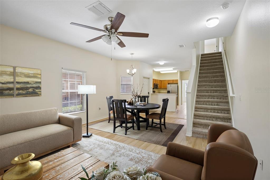 An open-concept living and dining area features a staircase, wood flooring, and a ceiling fan — 4244 BIRCH POND LOOP, LAKELAND, FL