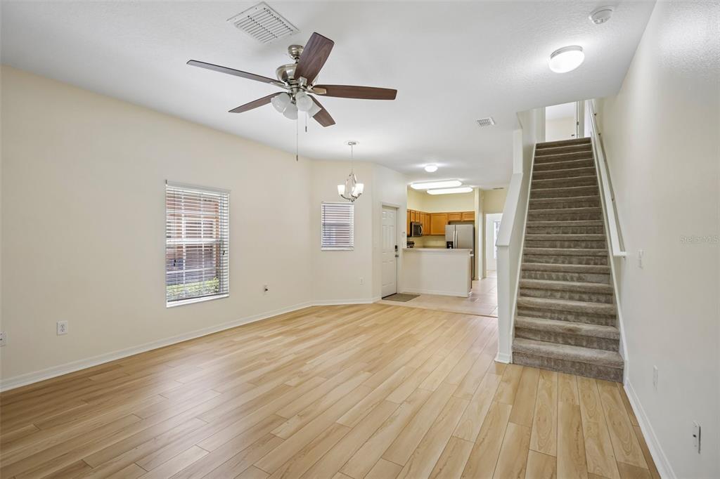 A living room with light wood flooring, a ceiling fan, and stairs leading to the upper level — 4244 BIRCH POND LOOP, LAKELAND, FL