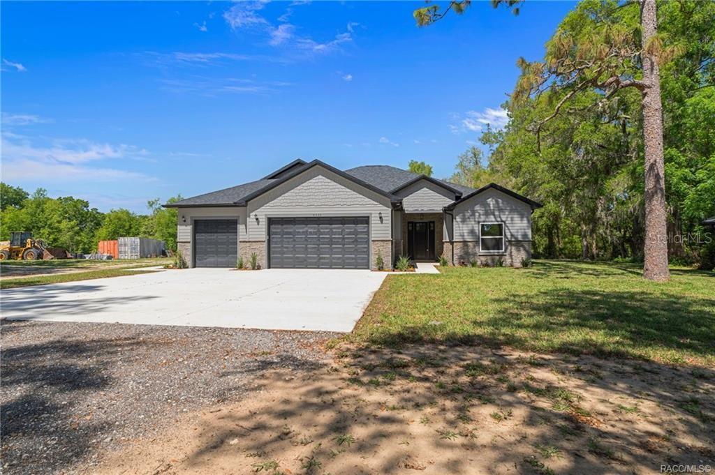 A single-story house with a gray exterior, stone accents, and a three-car garage — 4530 S FLORIDA AVENUE, INVERNESS, FL