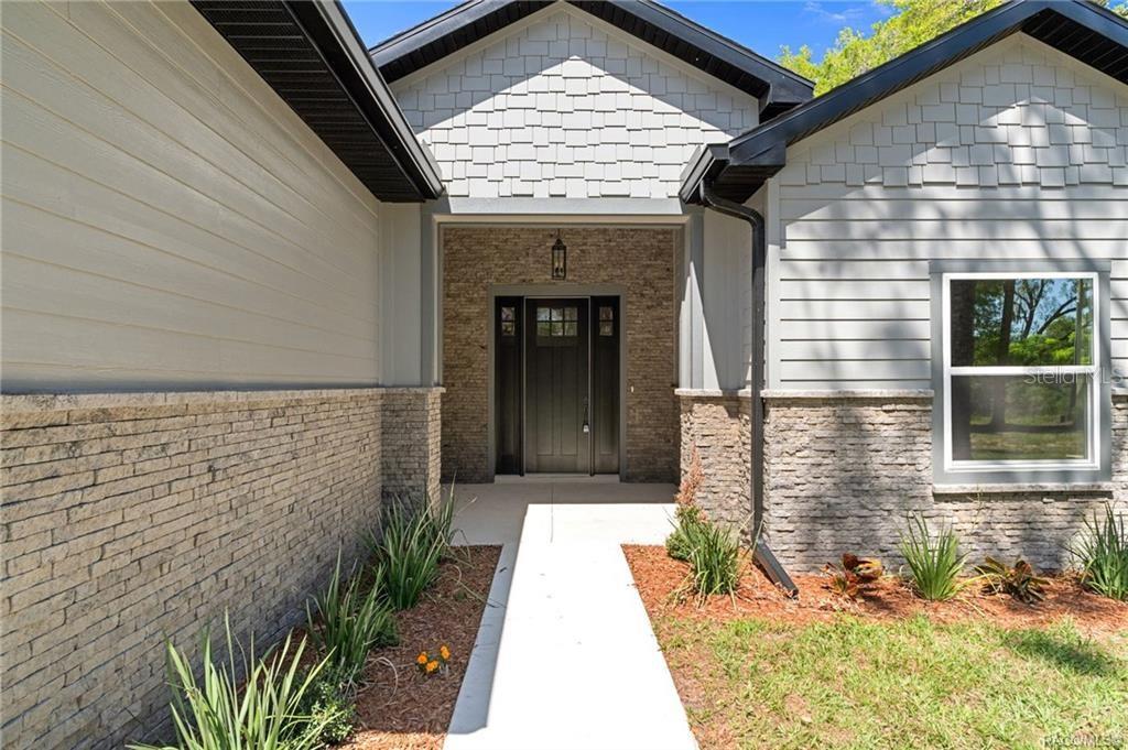 The exterior of a house features a stone-accented entryway, gray siding, and a concrete walkway — 4530 S FLORIDA AVENUE, INVERNESS, FL